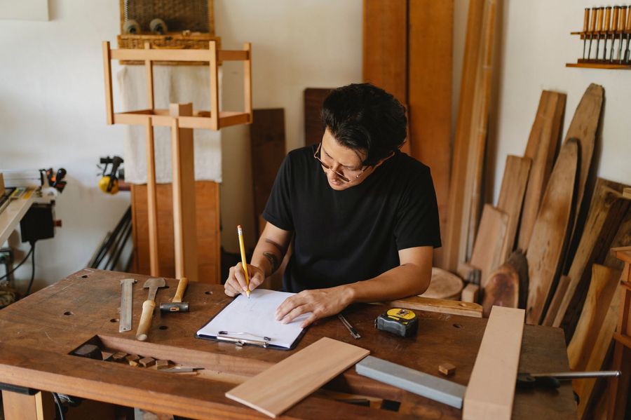 Un artisan remplit ses documents à son établi, au milieu de l'atelier